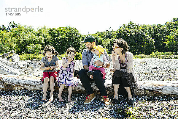 Direkter Blick auf eine Familie  die auf Treibholz im Carkeek Park sitzt