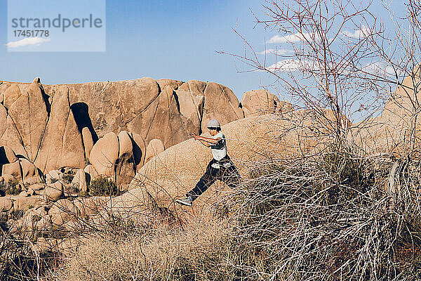 Teenager läuft zwischen Felsen in der Wüste.