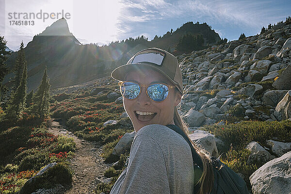 Nahaufnahme einer glücklichen Wanderin mit Sonnenbrille beim Blick in die Kamera
