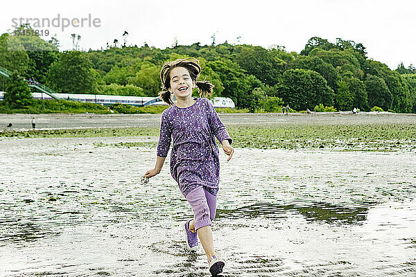 Vorderansicht eines jungen Mädchens  das über einen Strand in Seattle rennt
