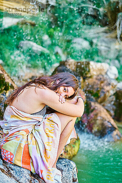 Junge Frau in einer Landschaft mit Wasserfall im Sommer