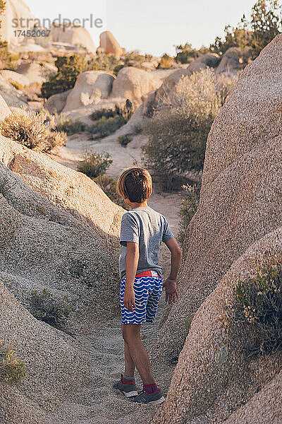 Grundschulkind geht auf einem Pfad aus Steinen in der Wüste spazieren.