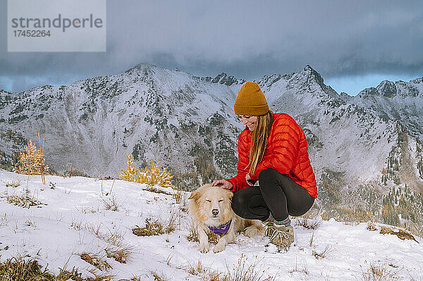 Einen süßen  flauschigen Hund auf einem verschneiten Berggipfel streicheln