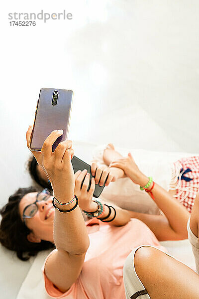 Mutter und Mädchen liegen auf dem Boden und machen ein Selfie und haben Spaß zu Hause