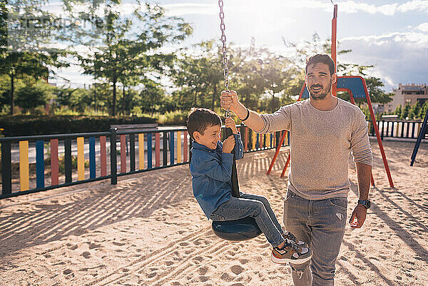 Vater und Sohn spielen mit einer Seilrutsche in einem Park