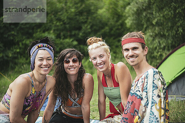 Bunte Gruppe queerer Freunde lächelt im Festivalcamp in der Natur