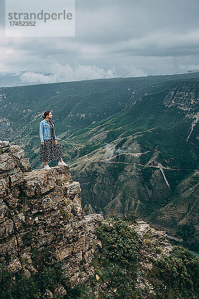 Eine reisende Frau steht am Rand einer Bergklippe und schaut zu