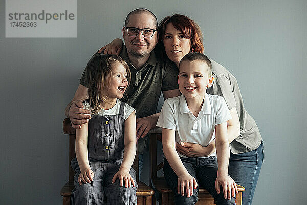 Porträt einer glücklichen Familie auf grauem Hintergrund zu Hause.