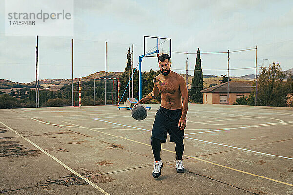Kleiner Junge trainiert alleine auf einem Basketballplatz