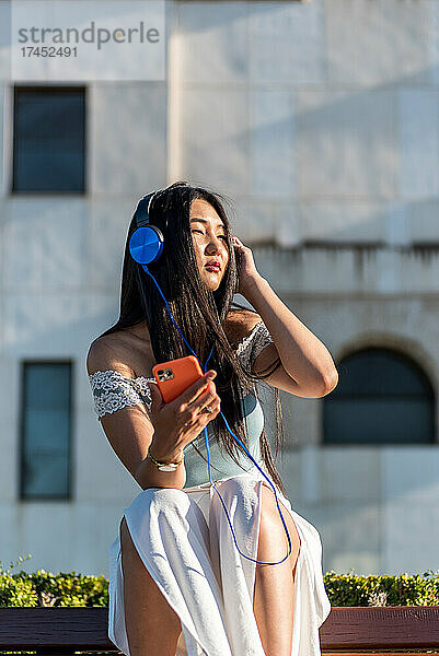 Asiatische Frau hört Musik mit Kopfhörern.