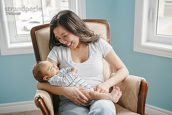 Stolz lächelnde chinesisch-asiatische Mutter hält neugeborenes Baby