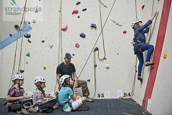 Klettertrainer unterstützt eine Gruppe von Mädchen an der Indoor-Kletterwand