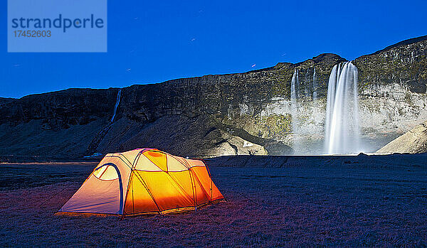 beleuchtetes Zelt am Wasserfall Seljalandsfoss im Süden Islands