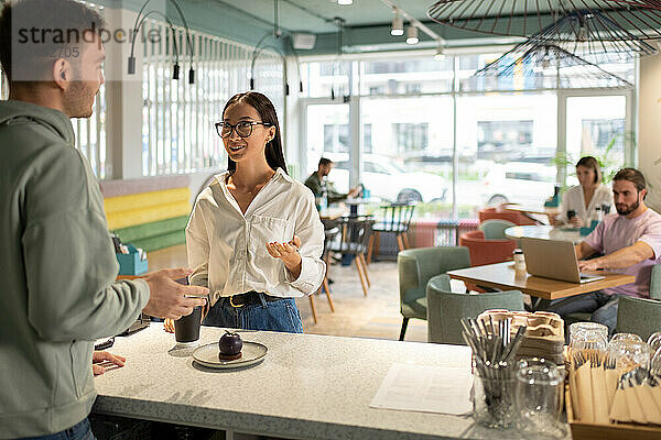 Frau unterhält sich mit Barista im Café