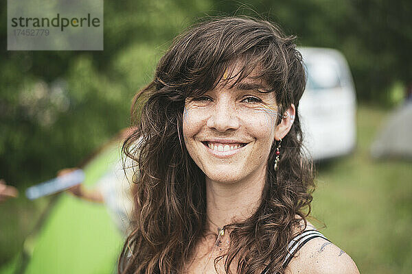 Lächelnde schöne Frau mit braunen lockigen Haaren  die auf einem Festival in Polen campt