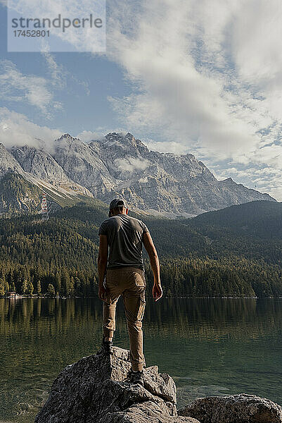 Mann steht auf einem Felsen am See