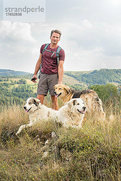 Erwachsener Mann wandert in der Natur mit Schäferhunden  auf den Hügeln in S