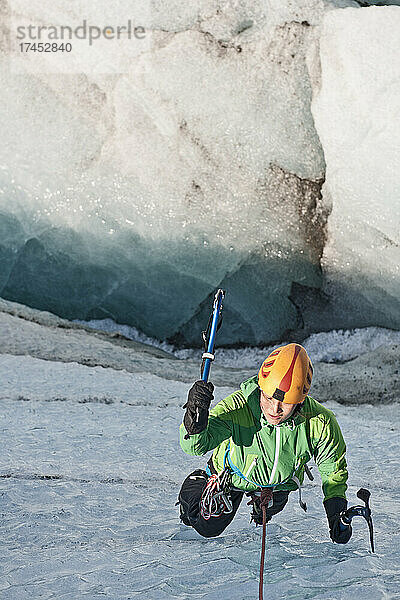 Frau klettert aus Gletscherspalte am Svinafellsjökull-Gletscher / Island