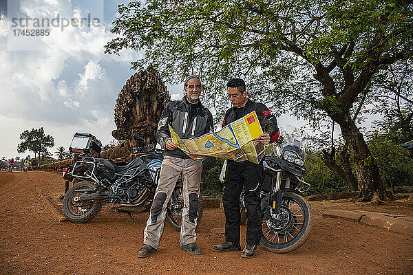 Zwei Männer schauen bei einer Abenteuer-Motorradtour in Kambodscha auf die Karte