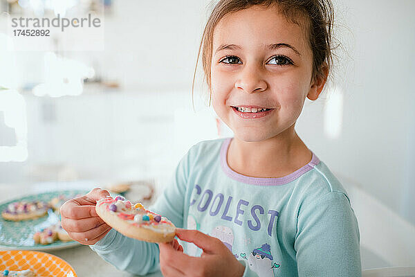 Junges Mädchen lächelt mit dekoriertem Osterplätzchen