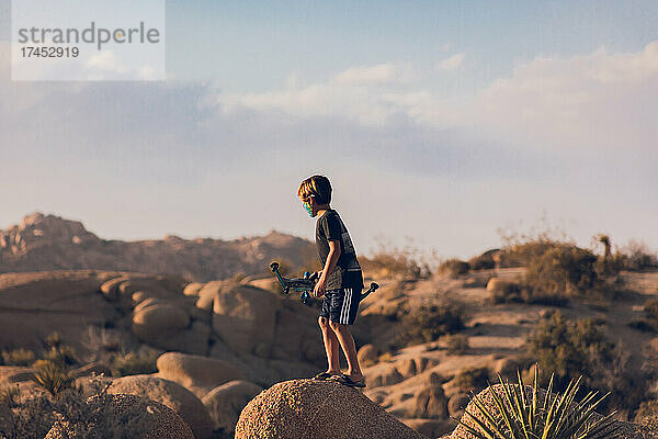 Junge spielt mit Pfeil und Bogen in der Wüste.