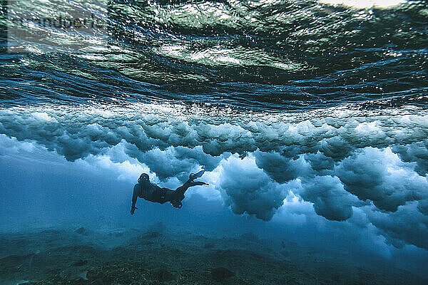 Mann schwimmt unter Wasser  winkt unter Wasser