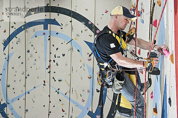 Mann legt Kletterrouten im Indoor-Kletterzentrum fest