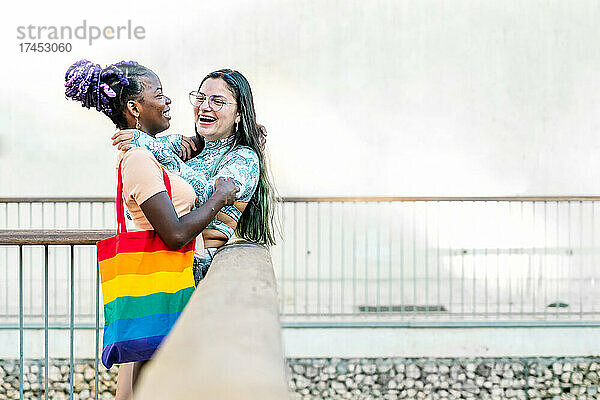 Glückliche homosexuelle  gemischtrassige Freundinnen  die sich auf der Straße umarmen