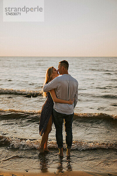 Ein verliebtes Paar küsst sich  während es im Meer steht.