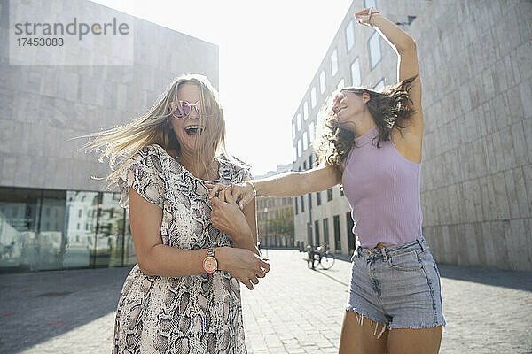 Zwei junge  glückliche Frauen tanzen in der Stadt München