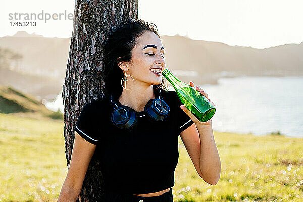 Junges hübsches kaukasisches Mädchen  das Bier trinkt und Musik hört