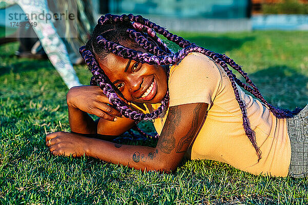 Schwarzes Mädchen mit Zöpfen posiert in einem Park