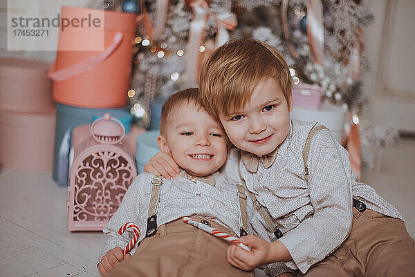 Fröhliche süße Kinderjungen  die Geschenke unter dem Weihnachtsbaum öffnen.