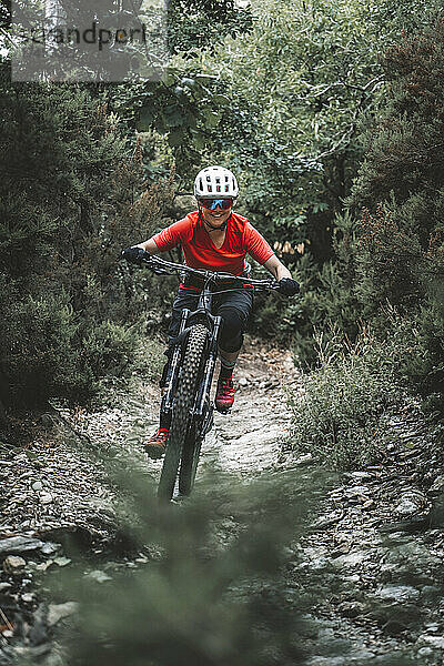 Rahmenfüllendes Aktionsporträt einer jungen Frau auf dem Mountainbike auf dem Weg