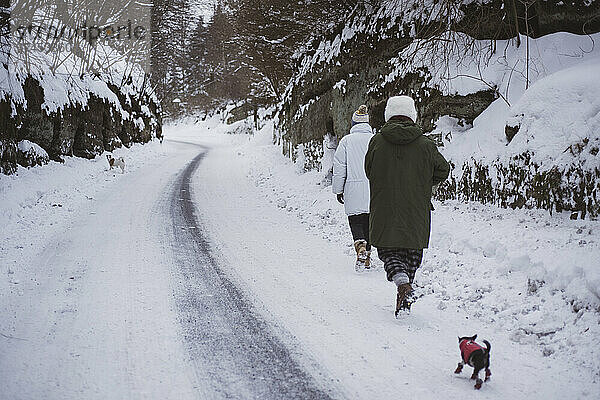 Zwei Personen in Schneejacken laufen durch die schneebedeckte Straße im tschechischen Winter