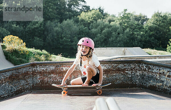 Mädchen lacht beim Skateboarden in einem Skatepark