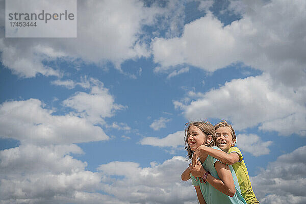 Fröhlicher lachender Junge und Mädchen vor dem blauen Himmel