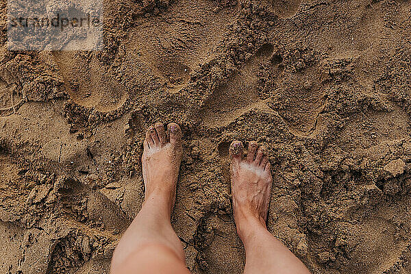 Nahaufnahme von nackten Füßen und sandigen Zehen am Strand von Waikiki bei Sonnenuntergang