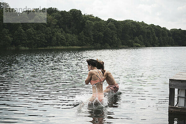 Freunde in Badeanzügen springen in einen See in Polen