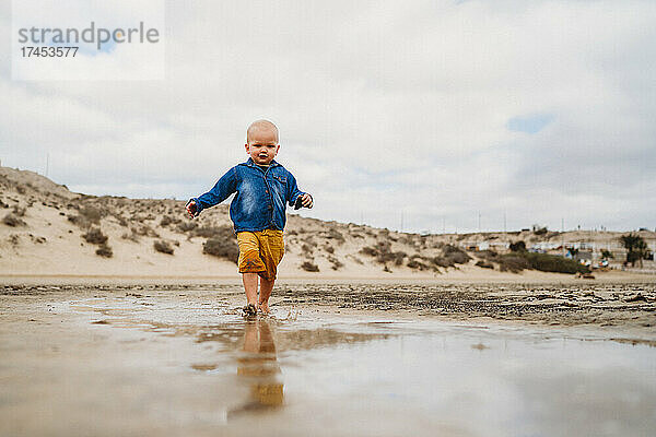 Netter Junge  der an einem bewölkten Tag am Dünenstrand von Fuerteventura spaziert