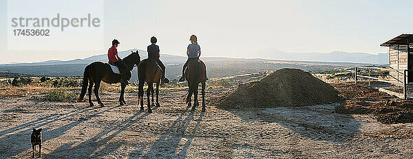 Panorama von drei Personen  die auf einem Pferd reiten und die Landschaft betrachten.