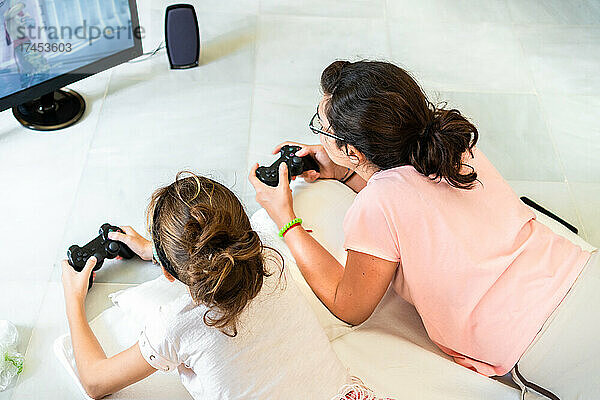 Draufsicht auf eine Familie  die zu Hause auf dem Boden liegt und gemeinsam Videospiele spielt
