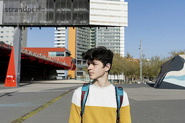 Junger Teenager steht mit Rucksack auf der Straße