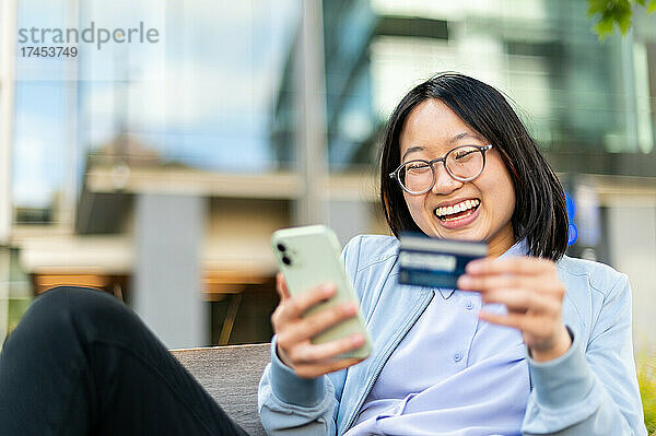 Glückliche junge Frau nutzt Mobiltelefon  um mobile Transaktionen durchzuführen