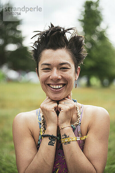 Lächelnde asiatische Mischlingsfrau mit lustigen Haaren auf einem Festival in Polen