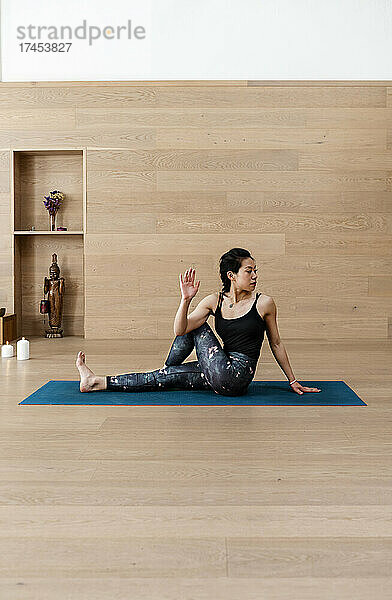 Asiatische Frau praktiziert Yoga und sitzt in der Pose „Halber Herr der Fische“.