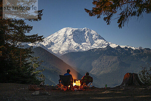 Silhouetten von Campern rund um das Feuer  dahinter der Mount Rainier