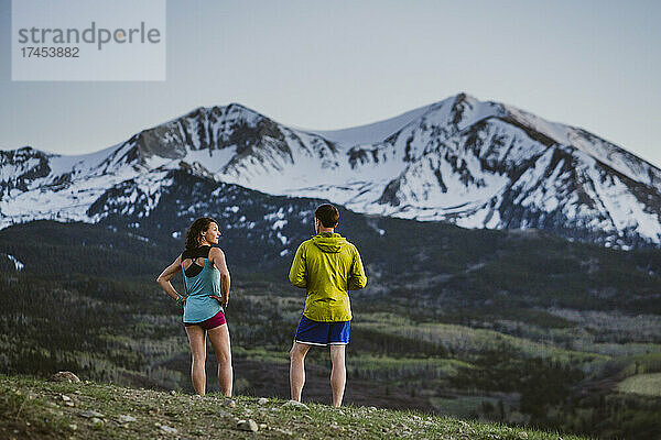 Zwei Freunde kommen beim Laufen vor einem großen Gipfel zu Atem