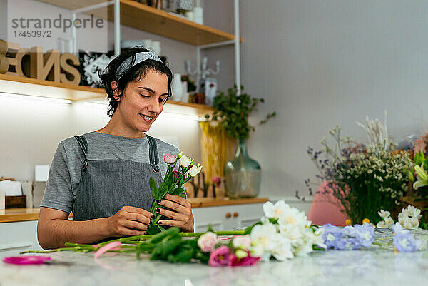 Eine junge Floristin stellt in ihrem Atelier einen Blumenstrauß zusammen