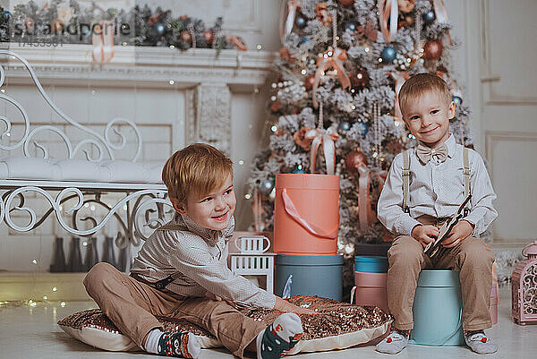 Fröhliche süße Kinderjungen  die Geschenke unter dem Weihnachtsbaum öffnen.